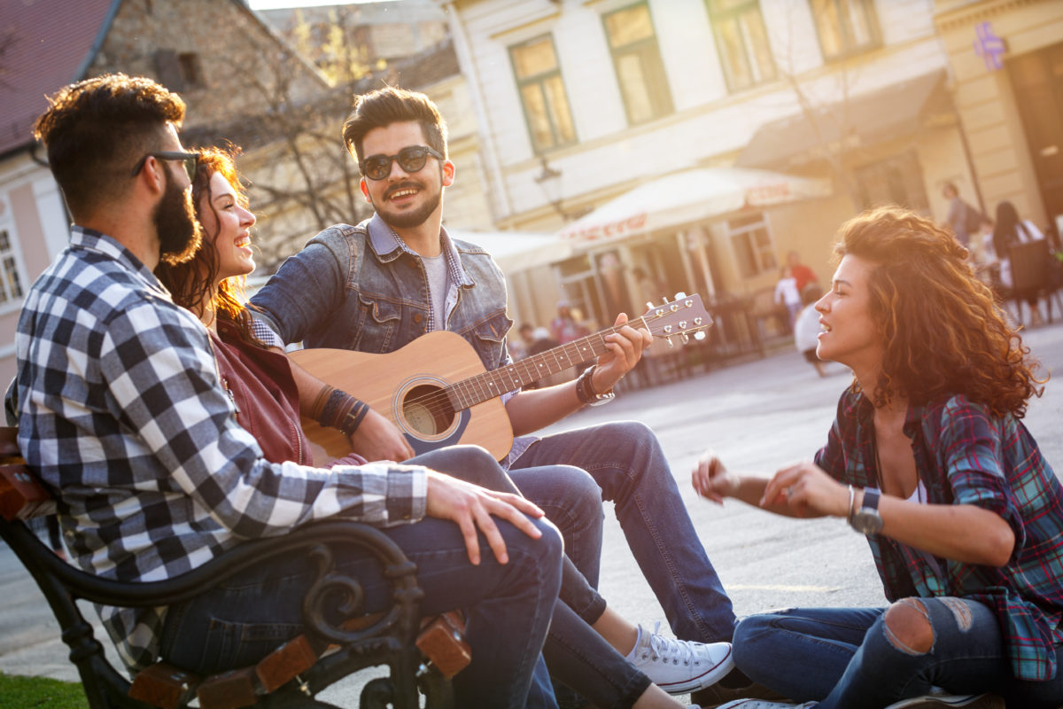 Group of people hangout at the city street.They sitting on bench ,singing and playing guitar. Group of people hangout at the city street.They sitting on bench ,singing and playing guitar.